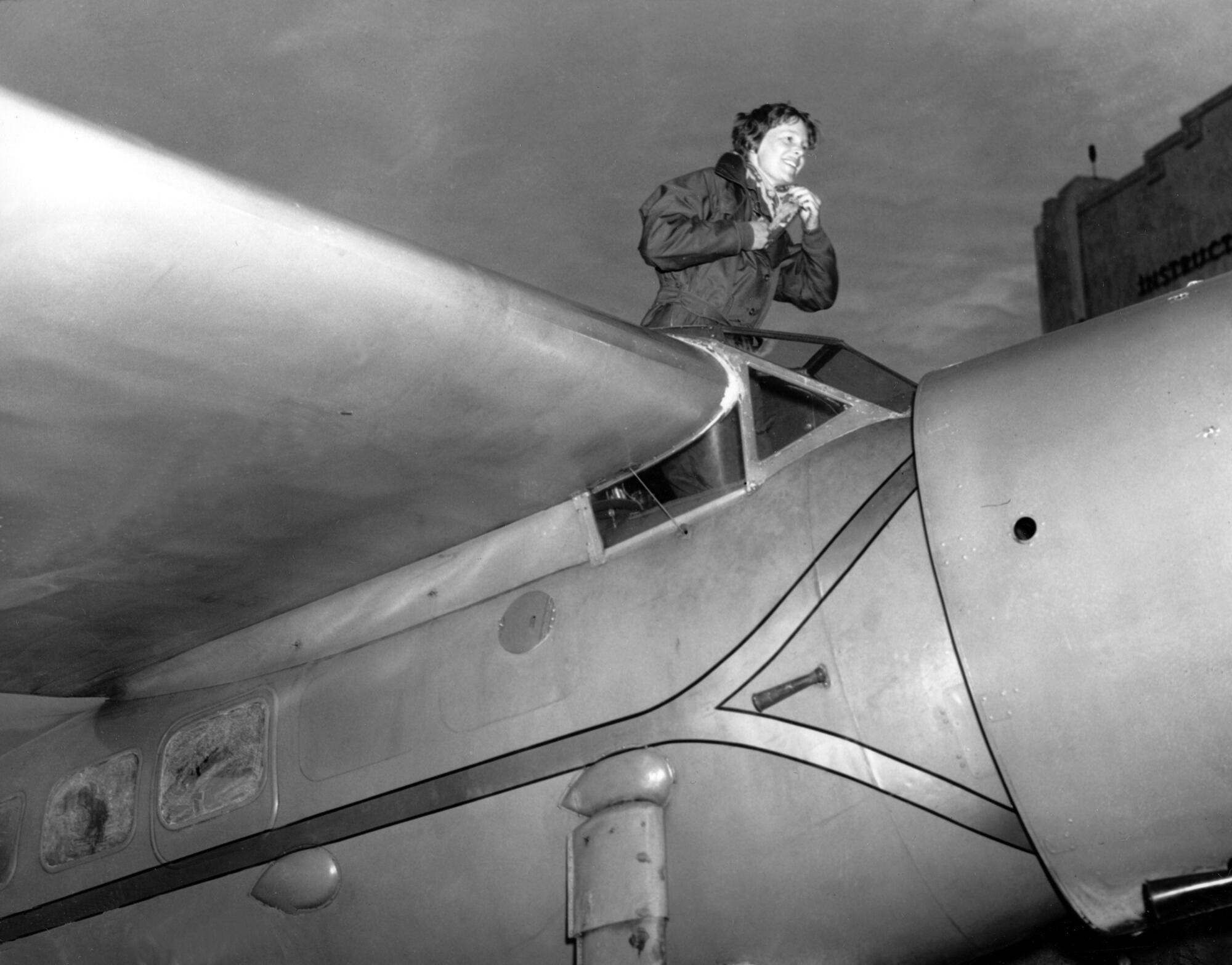 Amelia Earhart climbs from the cockpit of a plane
