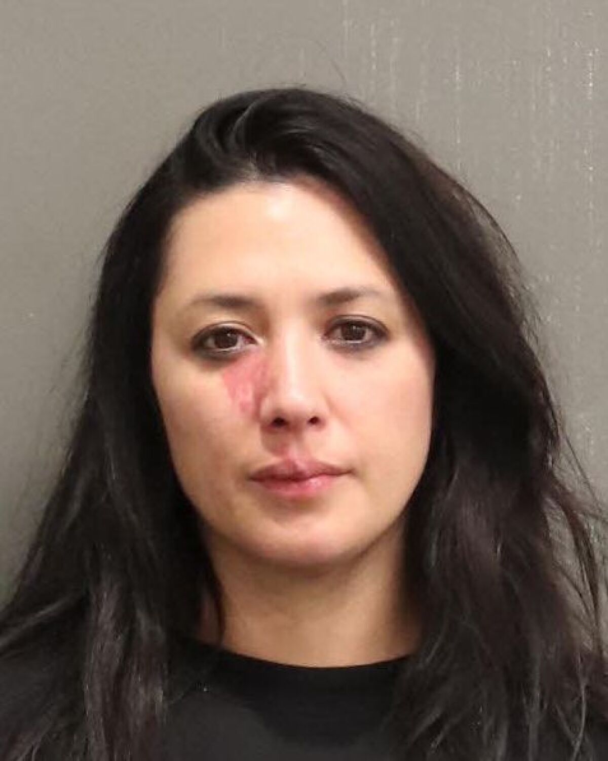 A mug shot of a woman with long hair showing redness below her right eye