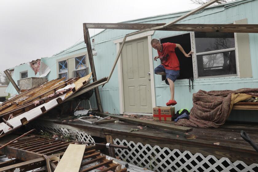 Sam Speights exits a window of his home that was destroyed in the wake of Hurricane Harvey in Rockport, Texas.