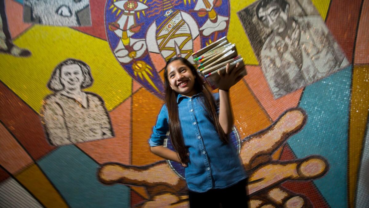 Leilany Medina, 11, holds a stack of books from her favorite series, "Judy Moody," at the East Los Angeles Library, where she "read away" late fees last week. Students won't have to worry about new late fees because of just-approved library rules.