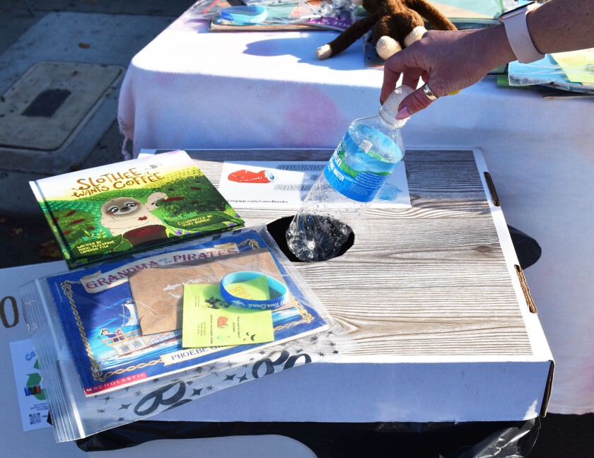 Someone recycling a plastic water bottle at the Cans4Books display during CicloSDias in Pacific Beach.