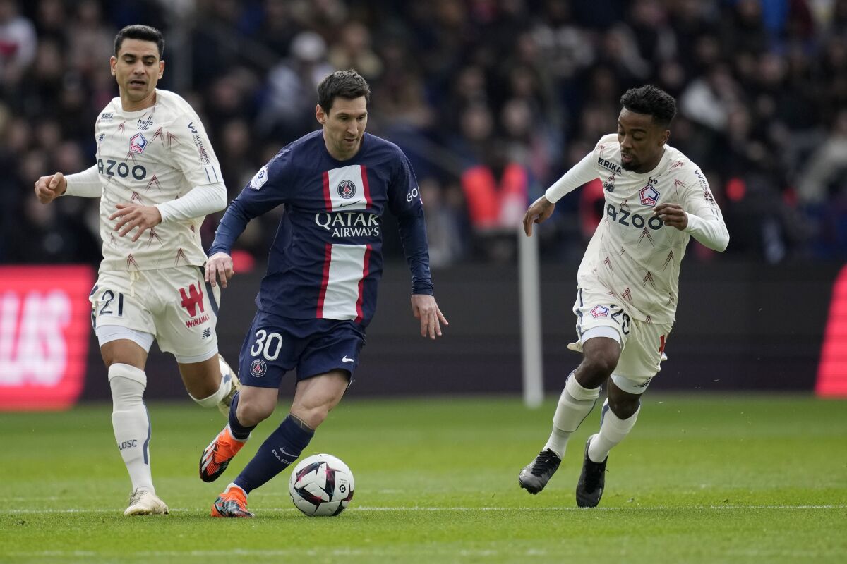 Lionel Messi (centro) del Paris Saint-Germain regatea ante Benjamin Andre (izquierda) y Timothy Weah de Lille en el partido de la liga francesa, el domingo 19 de febrero de 2023. (AP Foto/Christophe Ena)