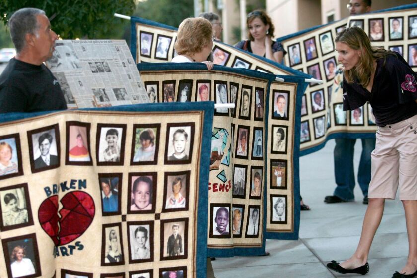 Documentary filmmaker Amy Berg looks at photos of alleged victims of sexual abuse by Catholic priests, during a protest by the Survivors Network of those Abused by Priests, or SNAP, outside the Cathedral of Our Lady of the Angels Wednesday, Sept. 27, 2006, in Los Angeles. In her first documentary "Deliver Us From Evil," Berg focuses on defrocked priest Oliver O'Grady's relationship with Los Angeles Cardinal Roger Mahony, who was his bishop in Stockton, Calif., in the early 1980s when O'Grady confessed to at least one instance of molestation. (AP Photo/Damian Dovarganes)