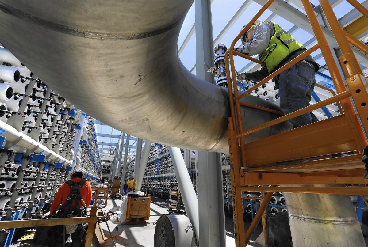 A pipe fitter installs a pressure relief valve on a pipe that will carry desalinated water from the Poseidon Water plant in Carlsbad.