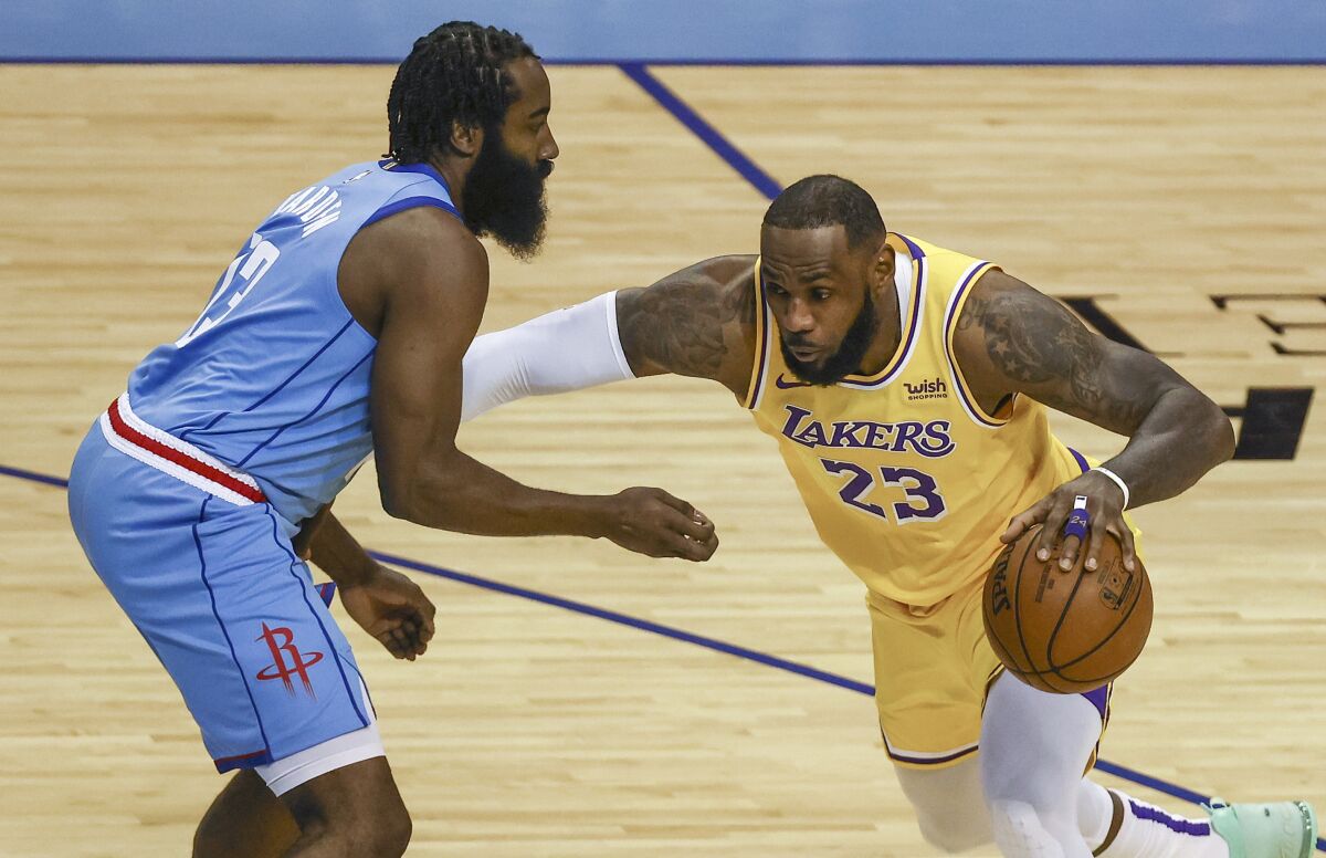 Lakers forward LeBron James drives with the ball against Houston Rockets guard James Harden.
