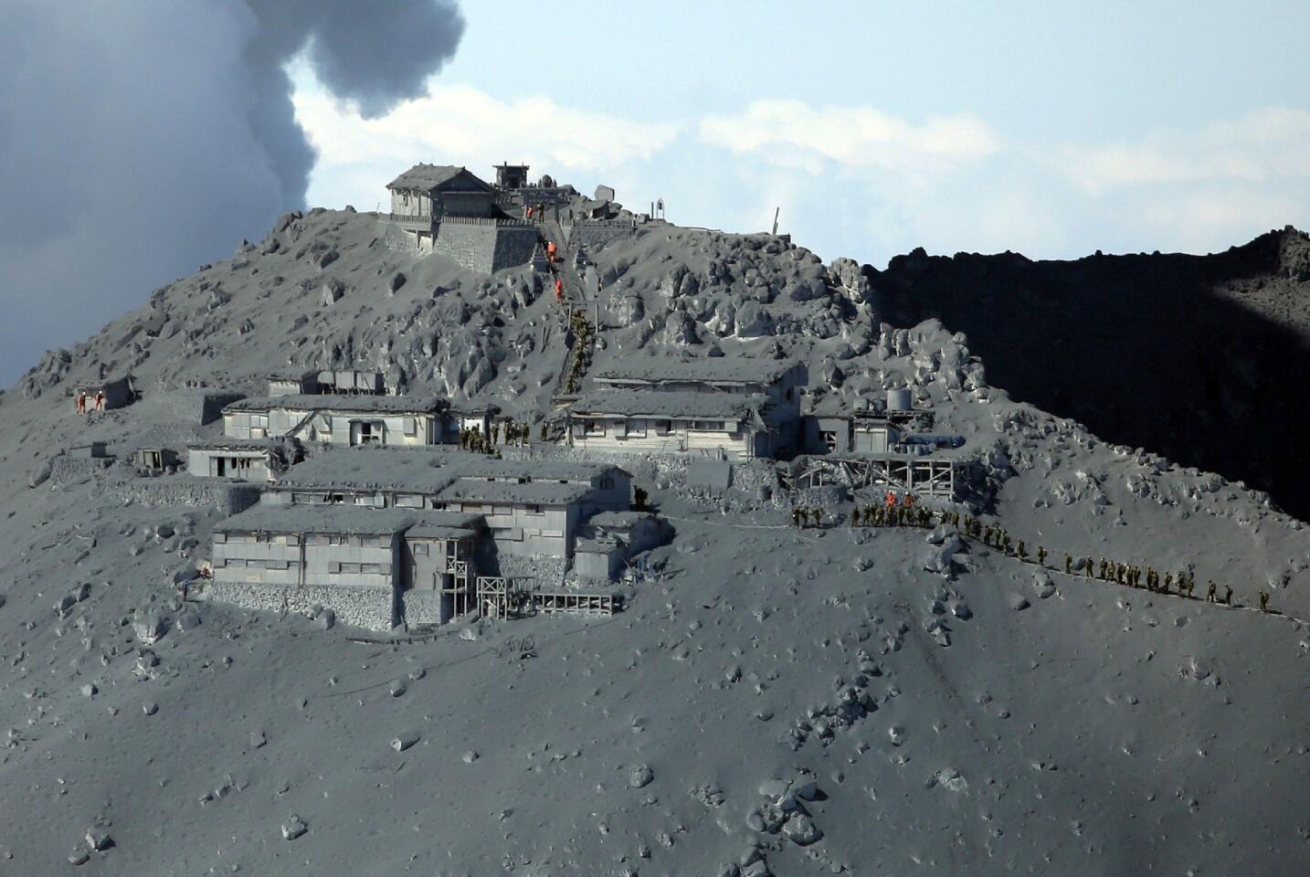An aerial photo shows rescue workers and soldiers searching for survivors among ash-covered cottages and a Shinto shrine on Sept. 28 after Japan's Mt. Ontake volcano erupted.