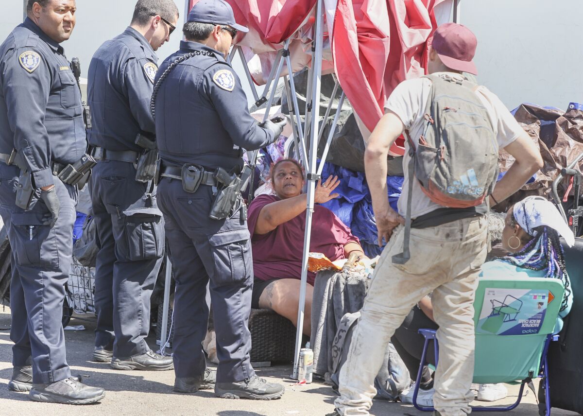  A woman talks with San Diego police officers during a crackdown on sidewalk encampments.