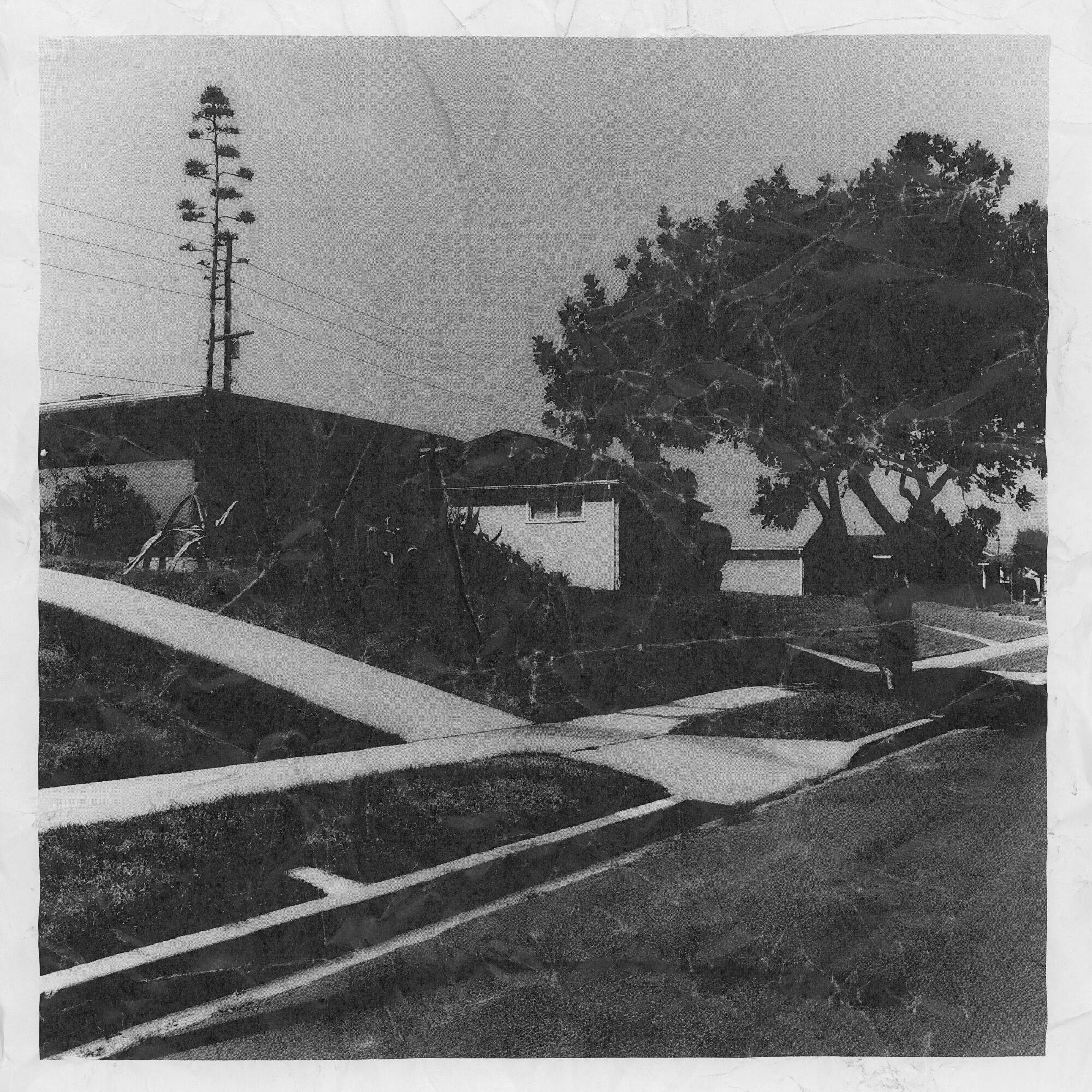 A wrinkled black and white photo of a house on a street.