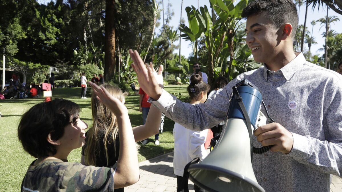 Ryan Abrishami, a senior at Beverly Hills High School and one of the student rally leaders, high-fives a younger student as they gather for a rally at Will Rogers Memorial Park.