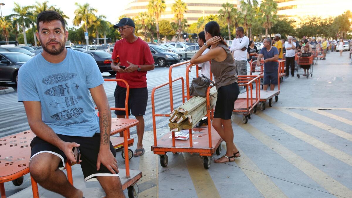 Max Garcia of Miami waits in line, where he has been since dawn, to purchase plywood at a Home Depot.