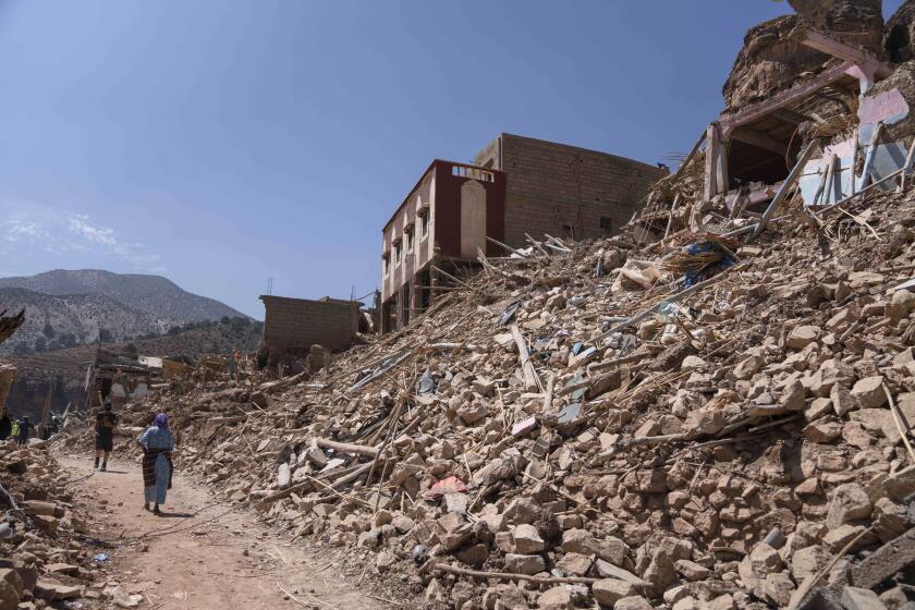 People walk amid the wreckage which was caused the earthquake, in the town of Imi N'tala, outside Marrakech, Morocco, Tuesday, Sept. 12, 2023. (AP Photo/Mosa'ab Elshamy)