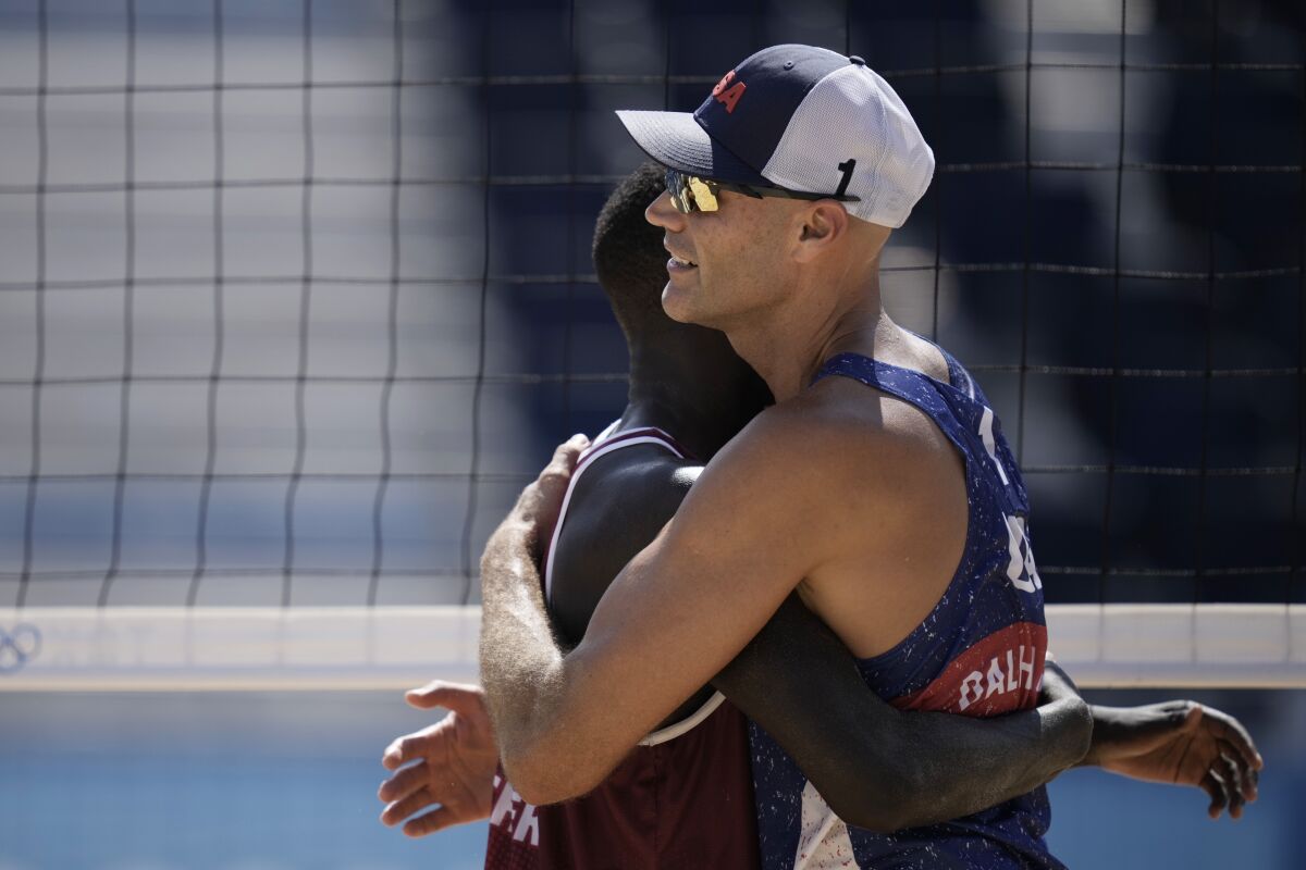 Cherif Younousse, left, of Qatar, hugs Philip Dalhausser, of the United States, after Qatar won a men's beach volleyball match at the 2020 Summer Olympics, Sunday, Aug. 1, 2021, in Tokyo, Japan. (AP Photo/Felipe Dana)