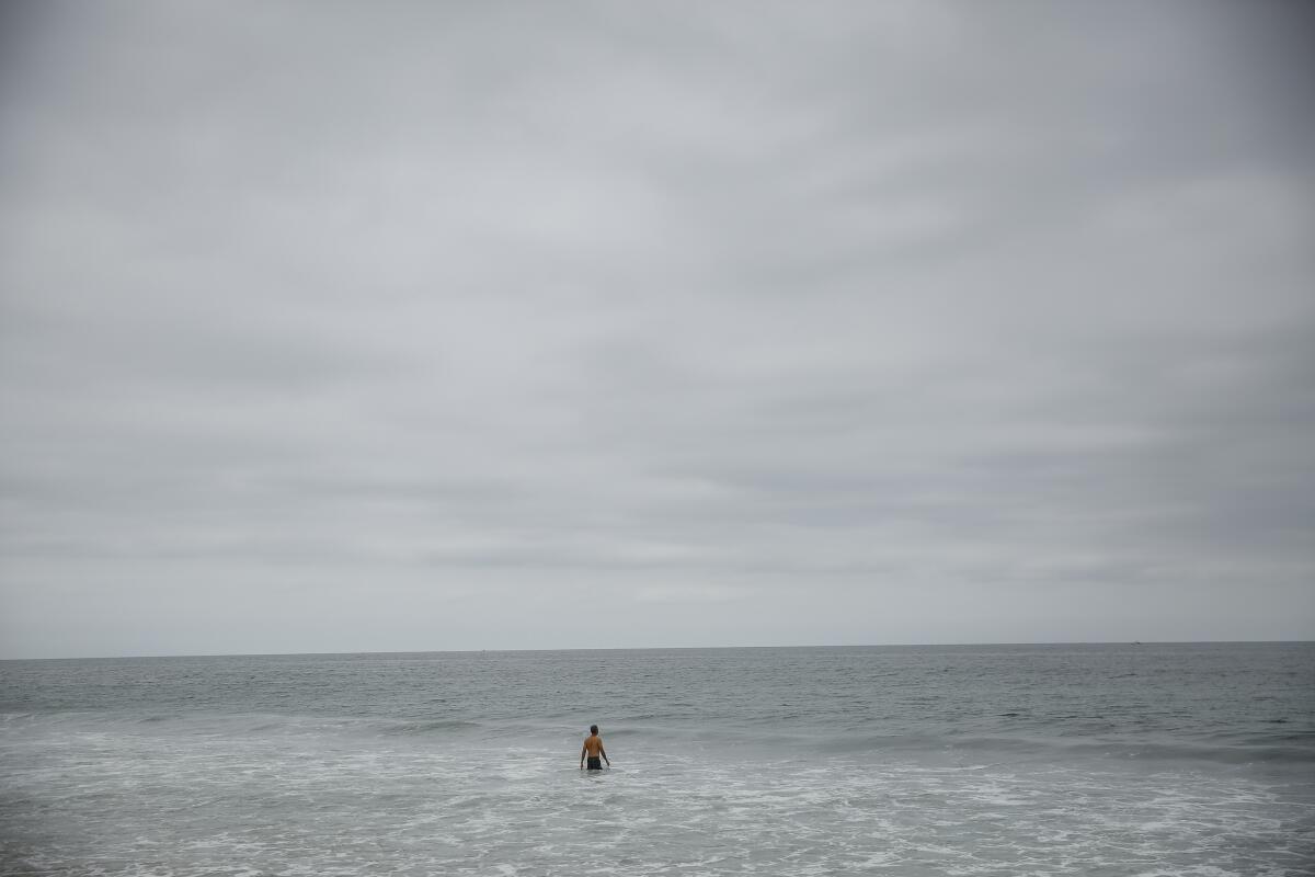 A man wades into the surf in Hermosa Beach under overcast June skies in 2018.
