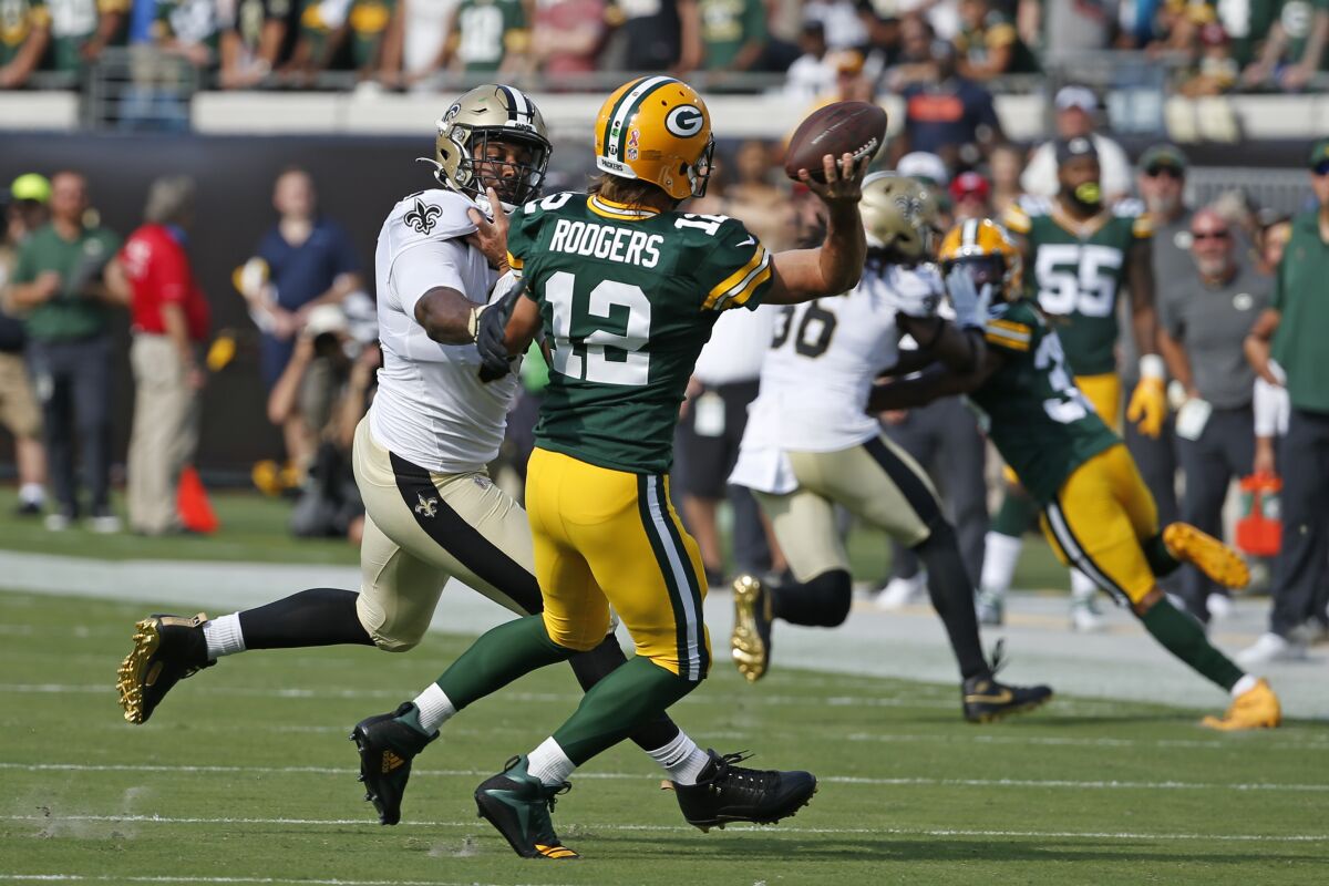 Green Bay Packers quarterback Aaron Rodgers (12) is his by New Orleans Saints defensive end Cameron Jordan, left, as he releases a pass during the first half of an NFL football game, Sunday, Sept. 12, 2021, in Jacksonville, Fla. (AP Photo/Stephen B. Morton)