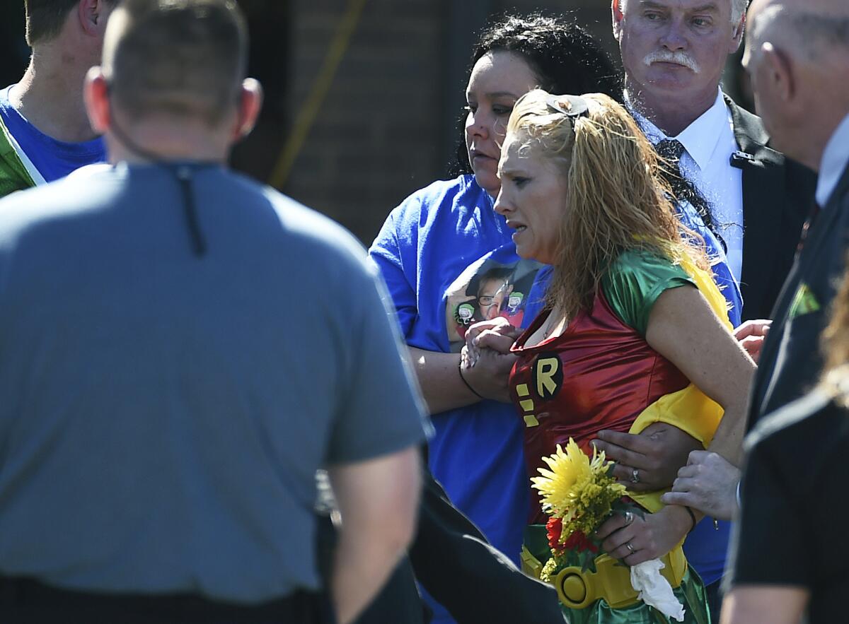 Renae Hall, right, mother of Jacob Hall, reacts as her son is placed into a hearse during his superhero-themed funeral.
