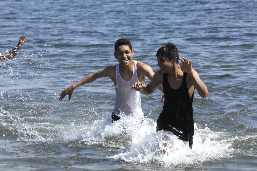 Los Angeles, California-April 7, 2022-Angel Reyes, age 15, left, and Justin Lewis, 14, right, both students from Green Design STEM Academy Learning Complex enjoy the water at Cabrillo Beach during a field trip on April 7, 2022. A heat wave is on its way to hit Los Angeles starting today. At Cabrillo Beach in San Pedro, (Carolyn Cole / Los Angeles Times)