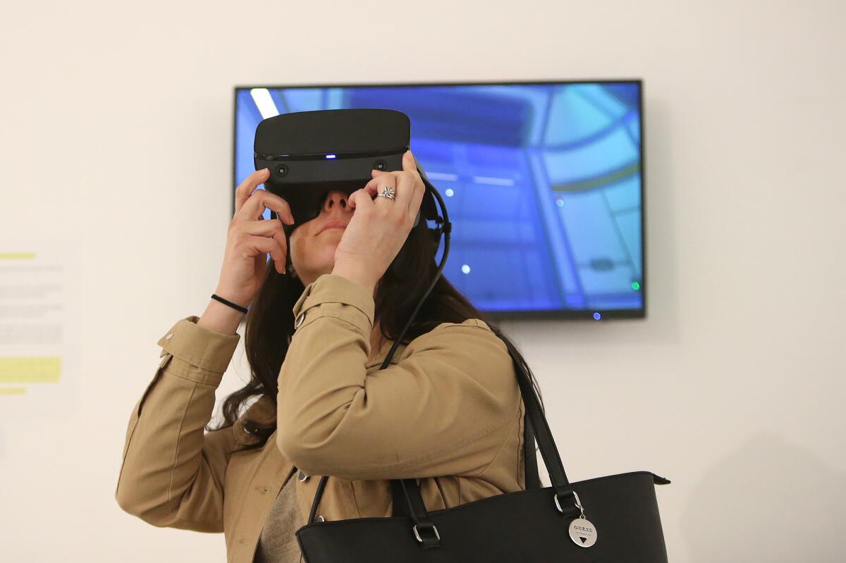 Melanie Garza uses a headset to experience a virtual reality narrative in the new exhibit "Immersion: Visions of the Singularity through VR/AR," featuring work by invited artists and students in the immersive media program at Orange Coast College in Costa Mesa. It is on display at the college's Frank M. Doyle Arts Pavilion.