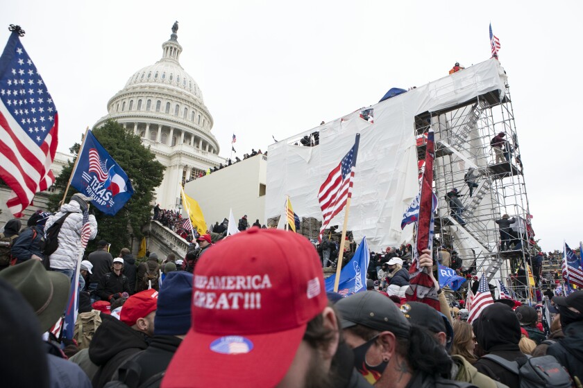 Supporters of President Donald Trump climb on an inauguration platform on the West Front of the U.S. Capitol on Wednesday.