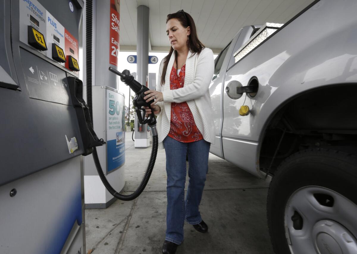 A woman holds the fuel nozzle at a gas station