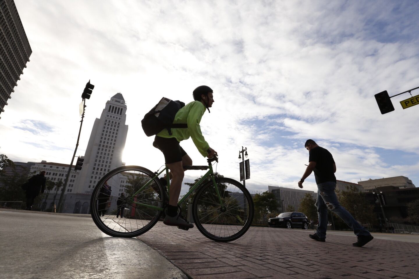 People walk and bike under blue-gray skies in downtown Los Angeles on Jan. 4 as a series of storms were forecast for Southern California.
