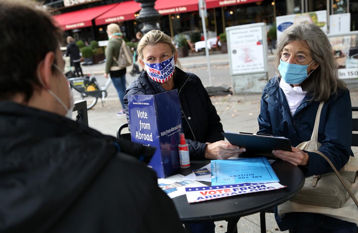 In Berlin, Florian Schiedhelm, from left, and Renee Johnsson help Emily Schalk to register for absentee vote in U.S. election