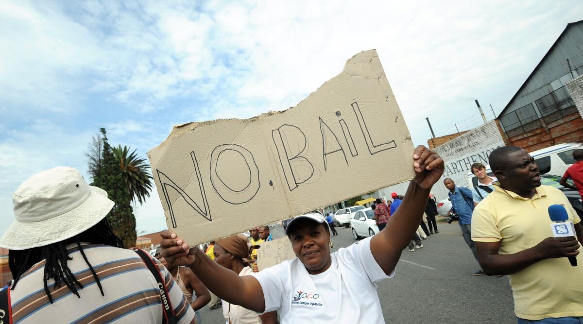 Protesters stand outside the Benoni court on Friday calling for no bail for the police officers charged with murdering Mido Macia.
