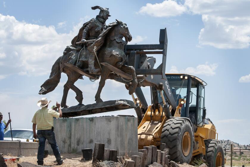 FILE - Rio Arriba County workers remove the bronze statue of Spanish conquerer Juan de Onate from its pedestal in front of a cultural center in Alcalde, N.M., June 15, 2020. A settlement has been reached in a civil lawsuit seeking damages from a 23-year-old man and his parents in the shooting of a Native American activist in northern New Mexico amid confrontations about the statue and aborted plans to reinstall it in public. The settlement was disclosed Tuesday, May 7, 2024, in court documents. (Eddie Moore/The Albuquerque Journal via AP, File)