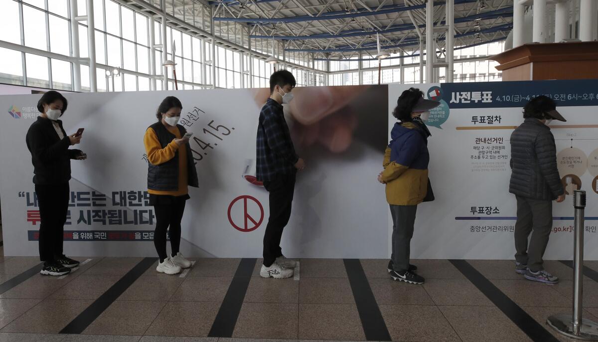 South Korean voters keep their distance while waiting in line in Seoul to cast their ballots during early voting.