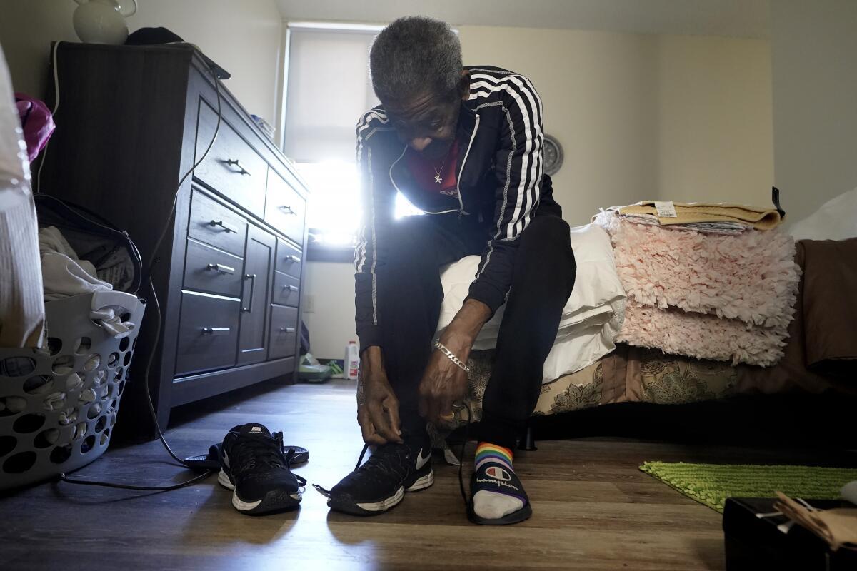 Steven Hamilton sits on his bed in his newly acquired apartment as he puts on sneakers before going for a walk.
