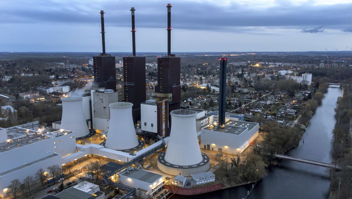 Three cooling towers loom over a gas-fired power plant complex in Berlin