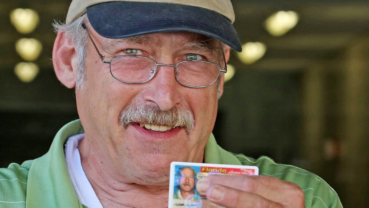 Benjaman Kyle places his fingers over his real name on his newly issued Florida ID card in September.
