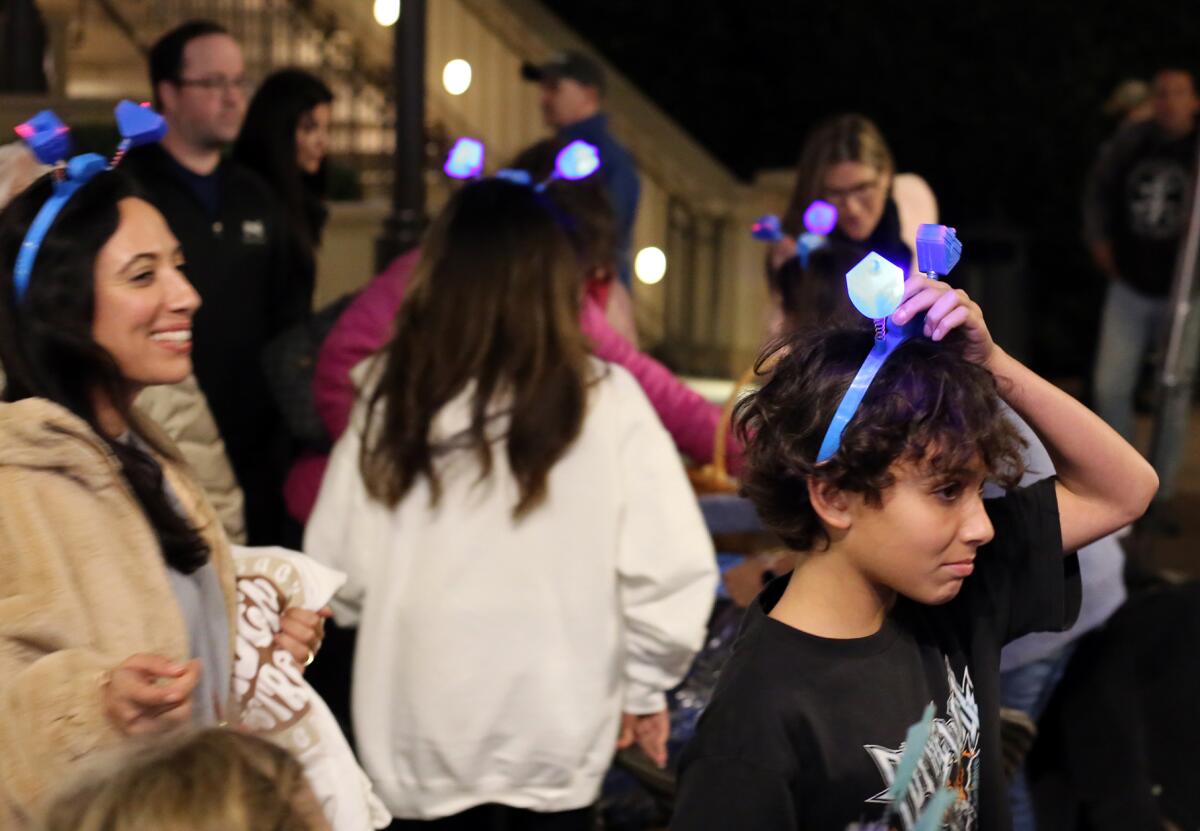 Families are all smiles as they are gifted a lighted blue dreidel headband at Thursday night's ceremony.