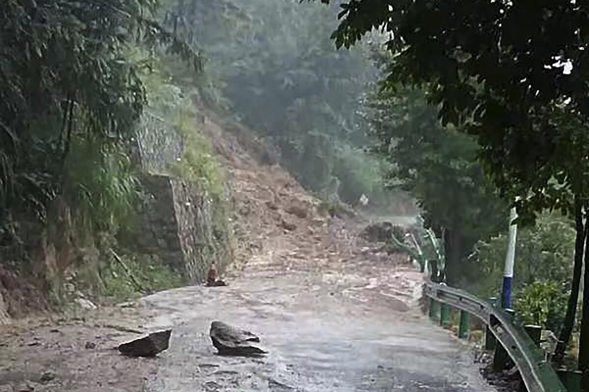 Debris from a mudslide covers a narrow road