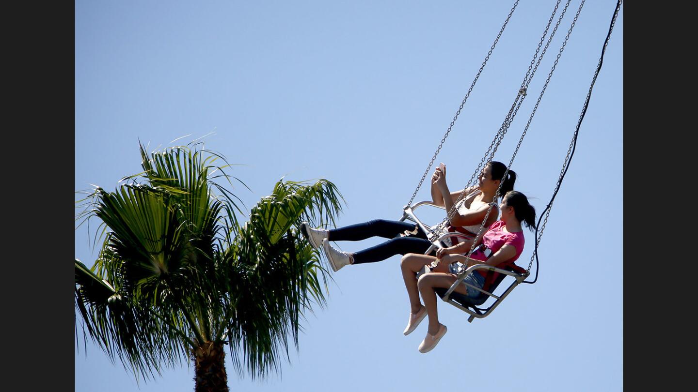 Sisters Farah, left, and Haya Eskender, of Glendale, seem to touch the palm trees, which were farther away than it seems, at the annual Incarnation Parish Carnival, in Glendale on Saturday, June 17, 2017.
