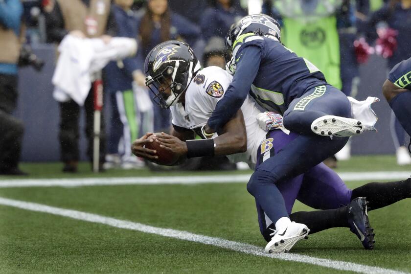 Baltimore Ravens quarterback Lamar Jackson (8) is hit by Seattle Seahawks cornerback Tre Flowers while scoring a touchdown on a fourth-down keeper play during the second half of an NFL football game, Sunday, Oct. 20, 2019, in Seattle. (AP Photo/Elaine Thompson)