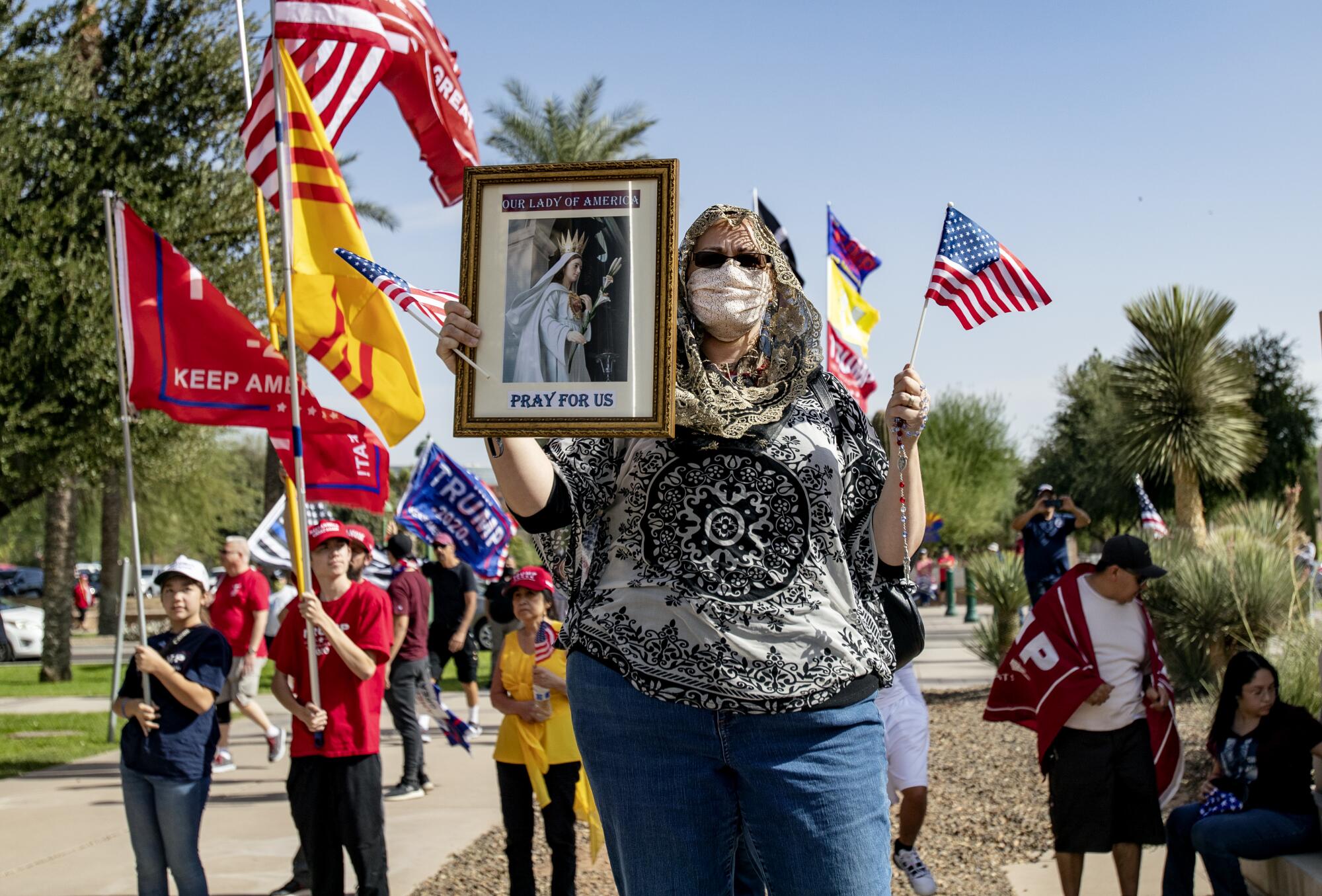 Trump supporter Elizabeth Lund holds her rosary and a religious photo at a "Stop The Steal" rally in Phoenix.