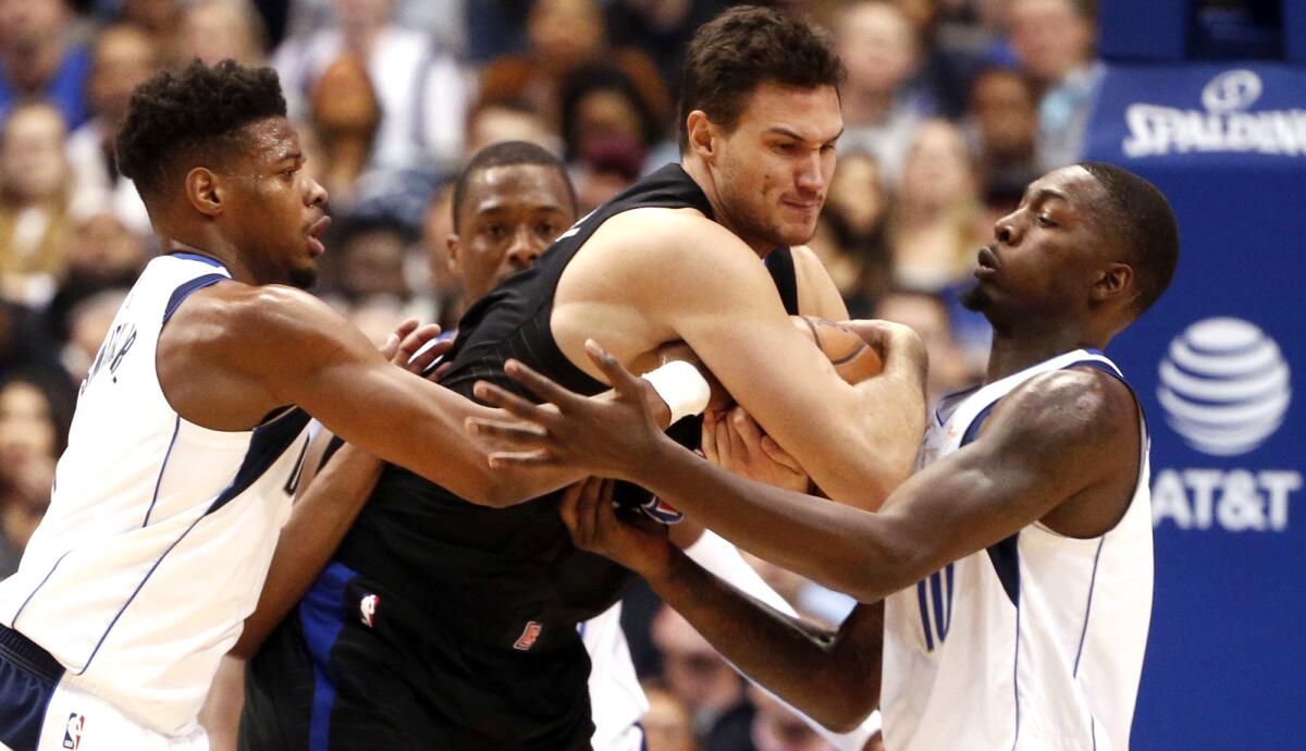 Clippers forward Danilo Gallinari draws the double-team defense by Mavericks guard Dennis Smith Jr., left, and forward Dorian Finney-Smith, who was called for a foul.