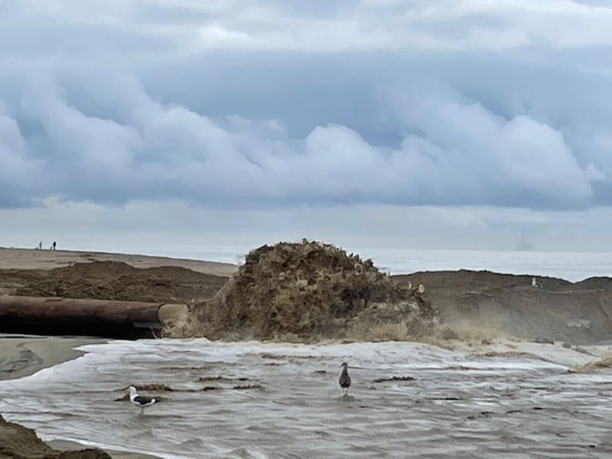 Mounds of dredged sand sit ashore on Surfside Beach.