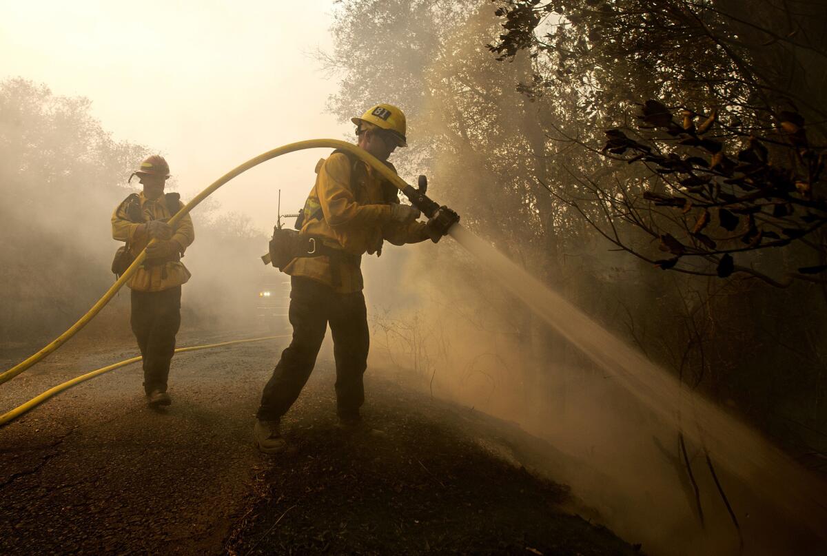 El bombero Tyler Zeller (d) apunta con su manguera a un foco de incendio con ayuda de Jesse Phillips en Sonoma, California.