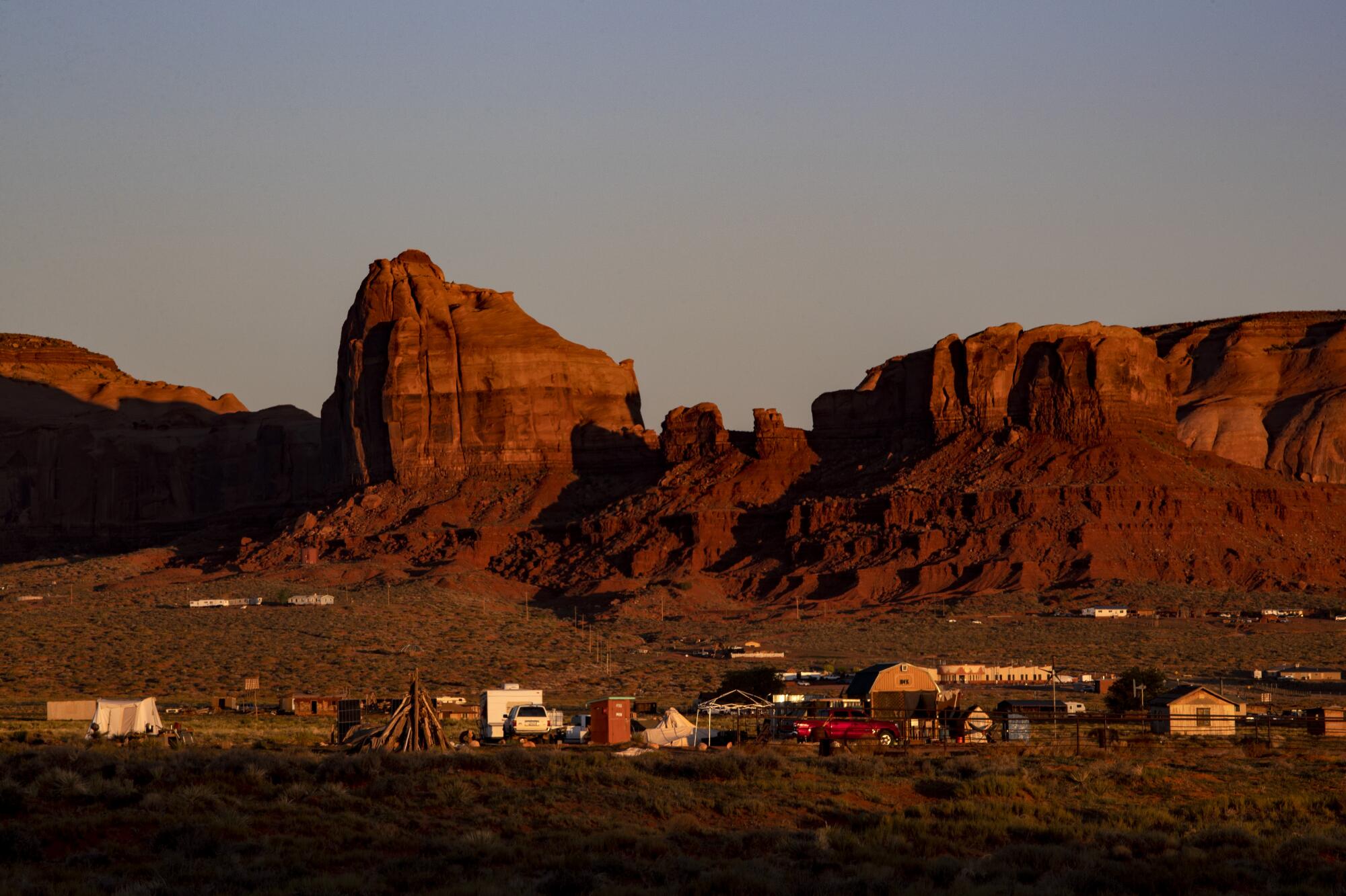 Dawn breaks over homes and sandstone formations near the Monument Valley Navajo Tribal Park