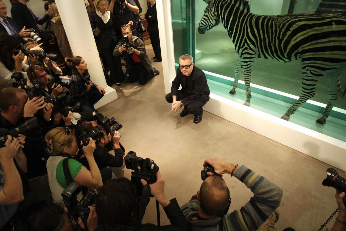 Damien Hirst is surrounded by a scrum of photographers as he poses for a portrait before a zebra in a tank of formaldehyde.