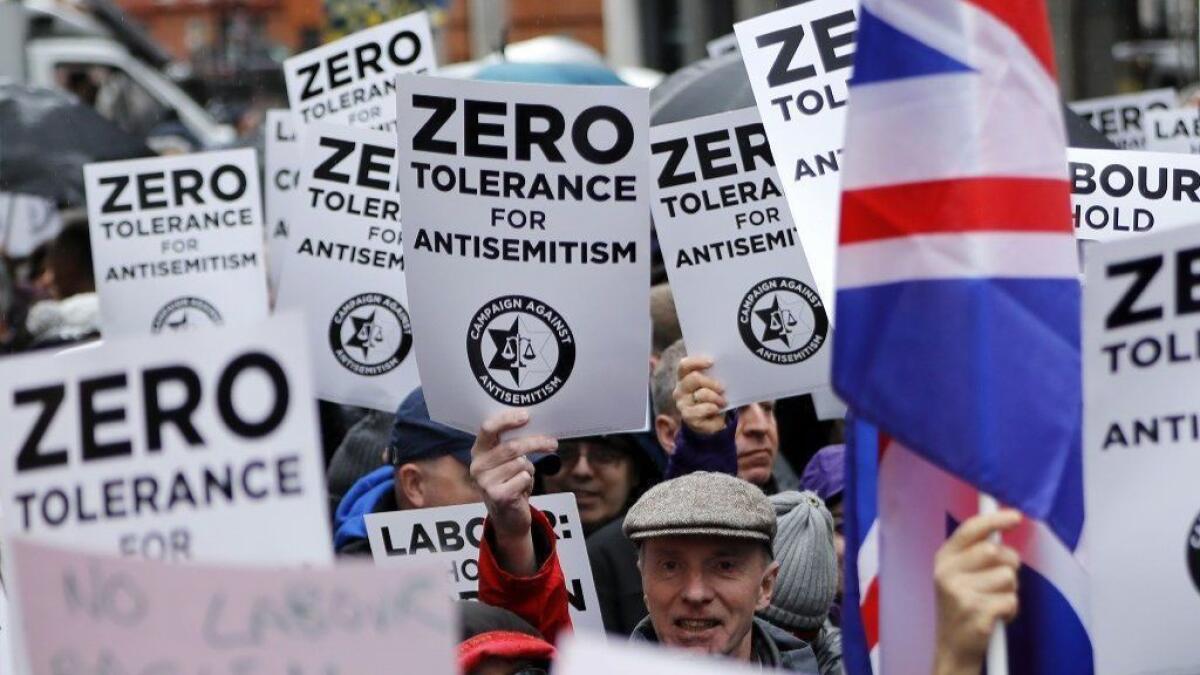 People hold up placards during a demonstration in London organized by the Campaign Against Anti-Semitism on April 8.