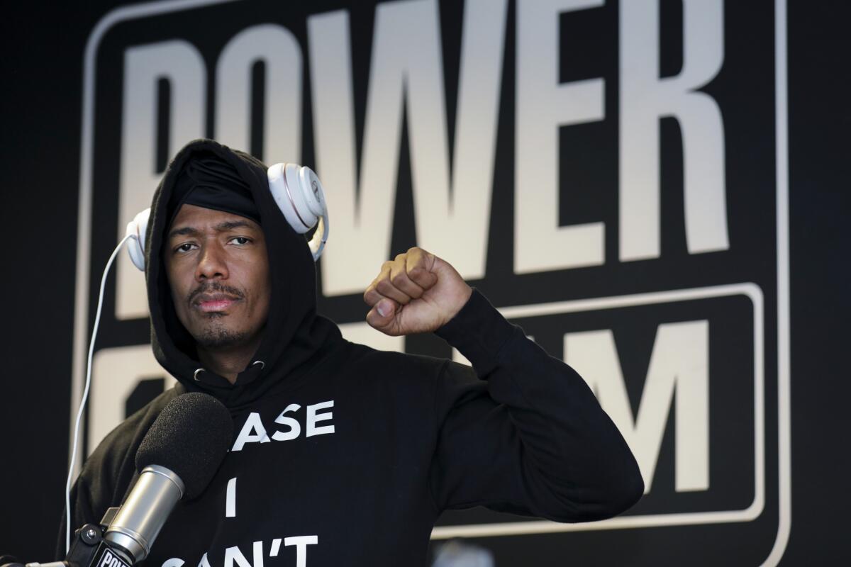 Nick Cannon in headphones in front of a microphone.