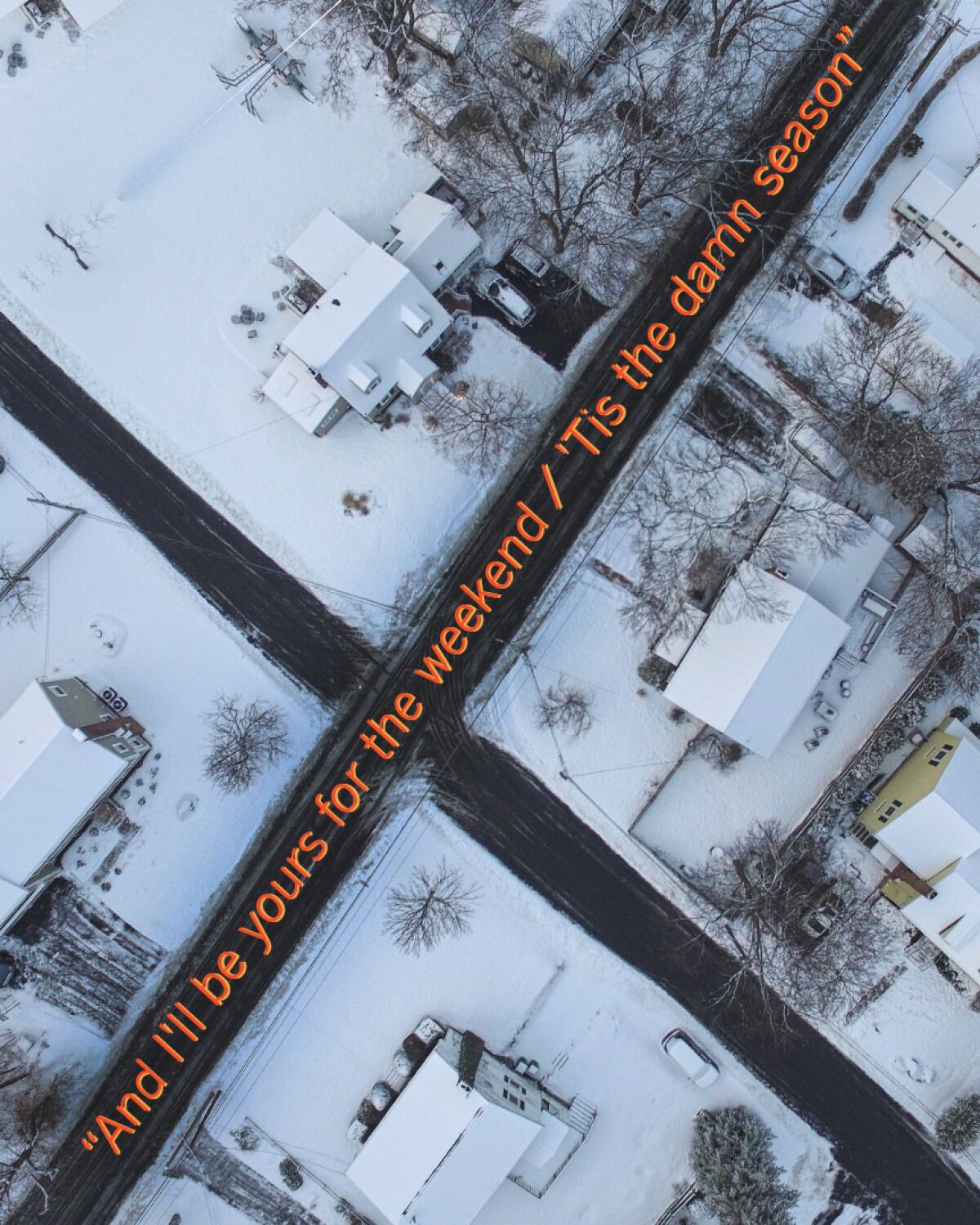 aerial shot of snowy town street. Lyrics from Taylor Swift's "'tis the damn season" splay across
