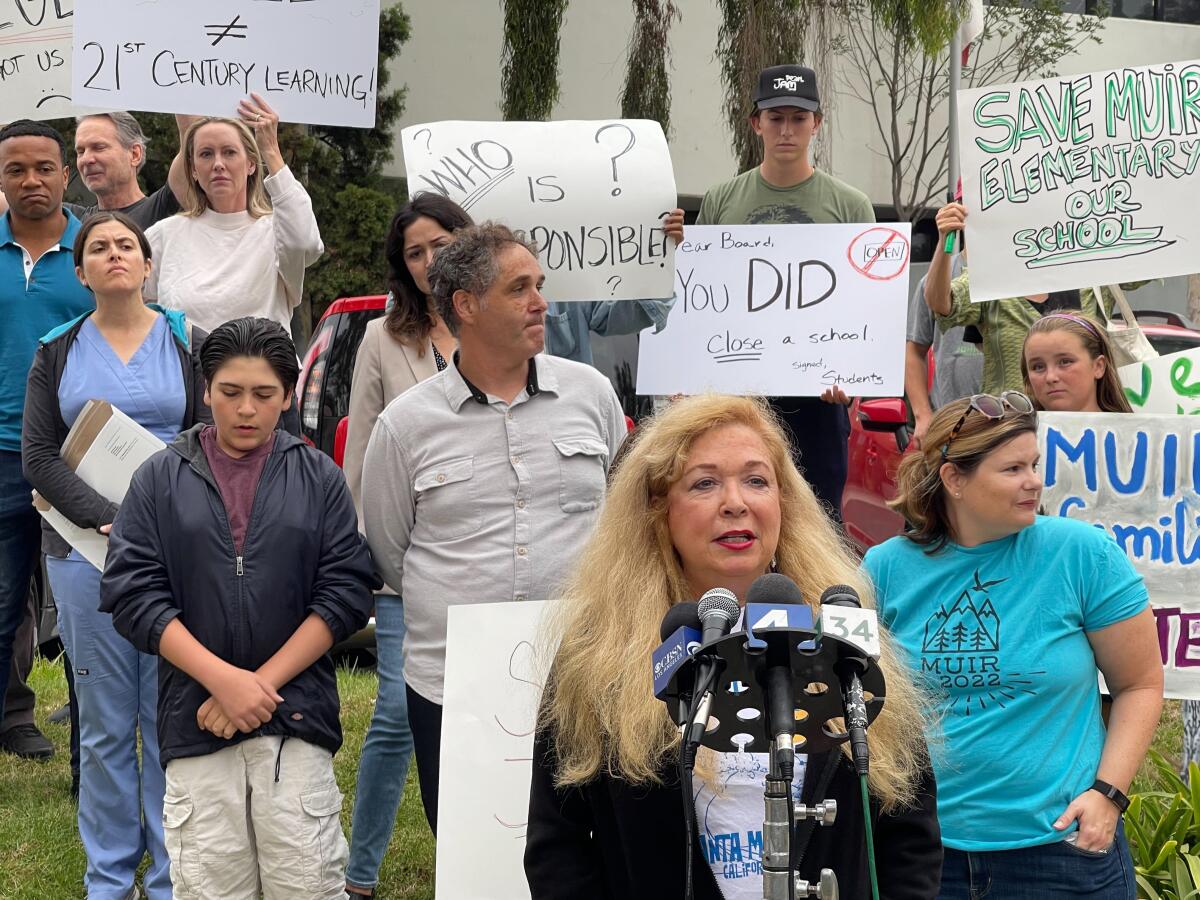 Parents hold signs at a rally during a news conference.