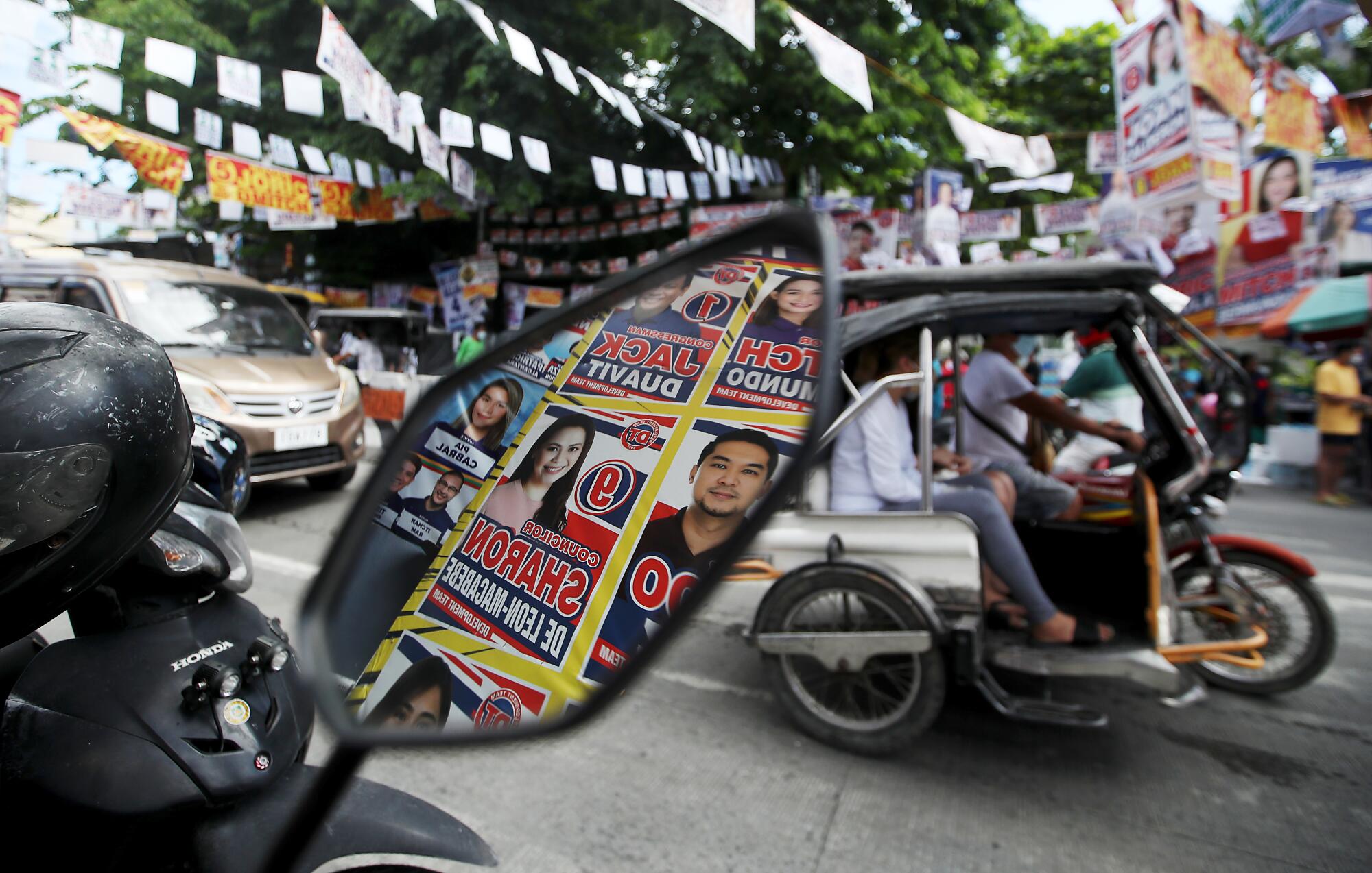 Campaign posters are reflected in the mirror of a motorcycle.