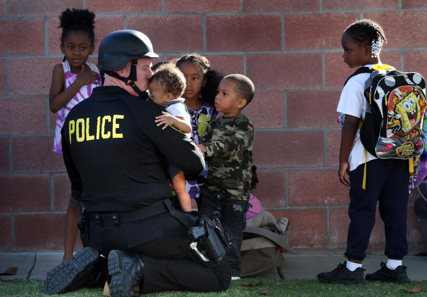 Inglewood police officer Joey Zeller kisses the head of a toddler he led to safety with a group of others from the neighborhood where two fellow officers were injured.