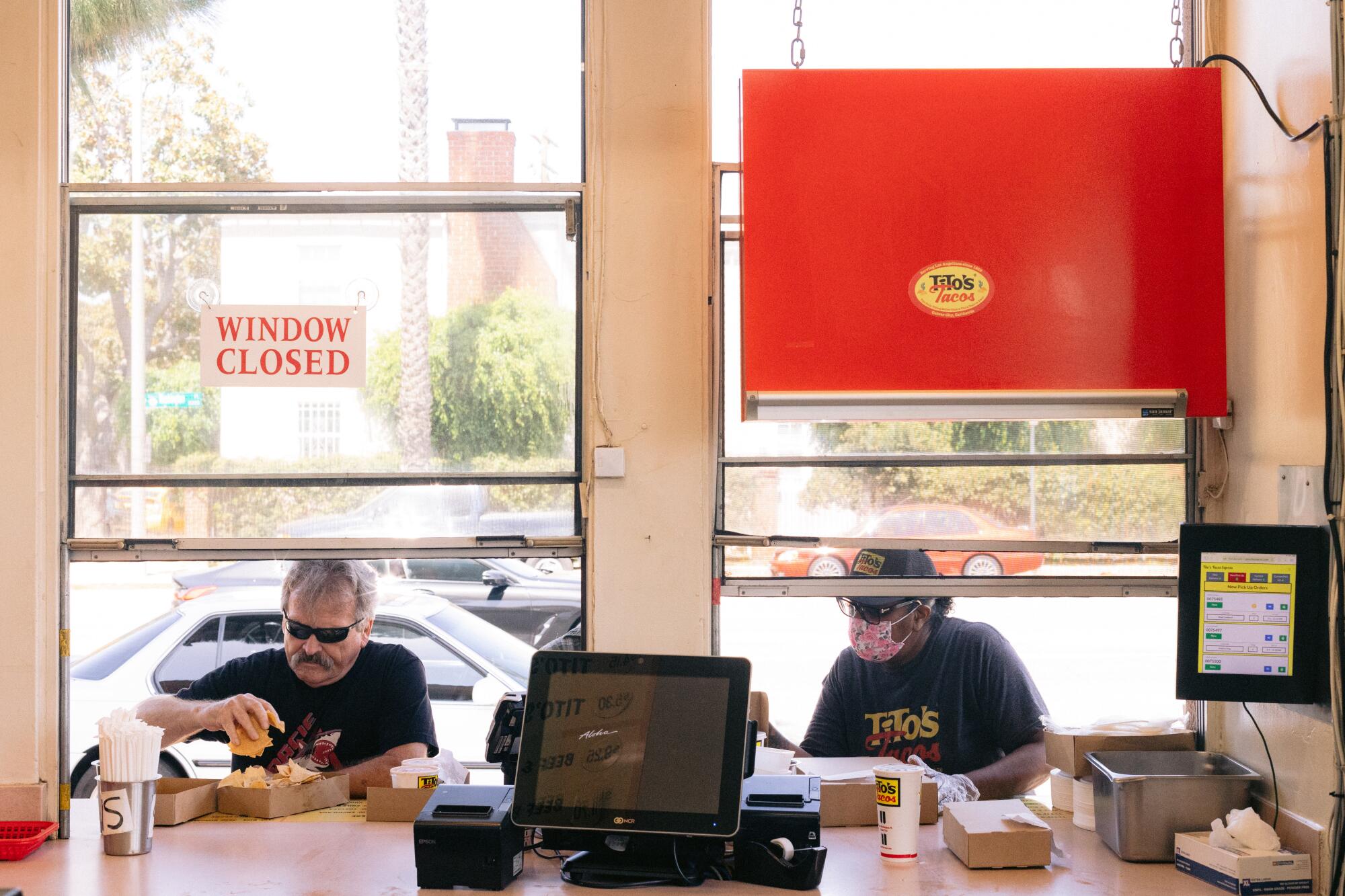 A view from the inside of Tito's Tacos as customers stand in the order windows.