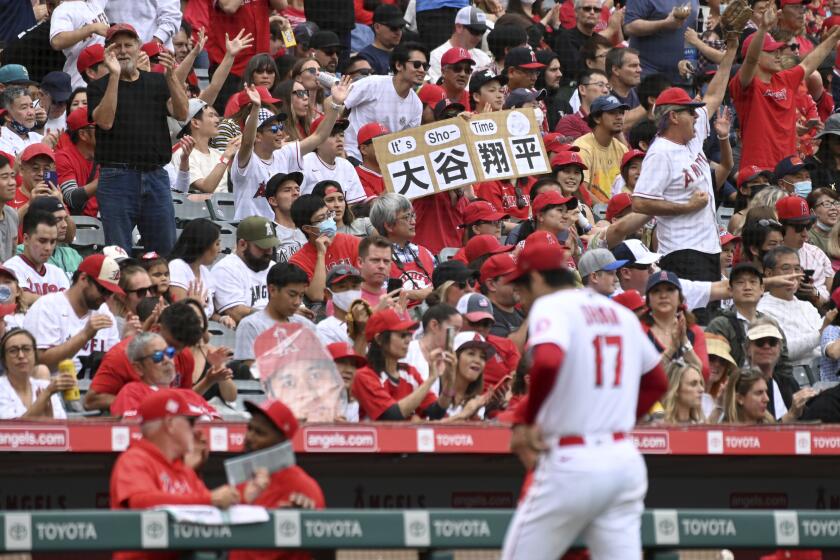 Angels fans applaud as pitcher Shohei Ohtani walks to the dugout.