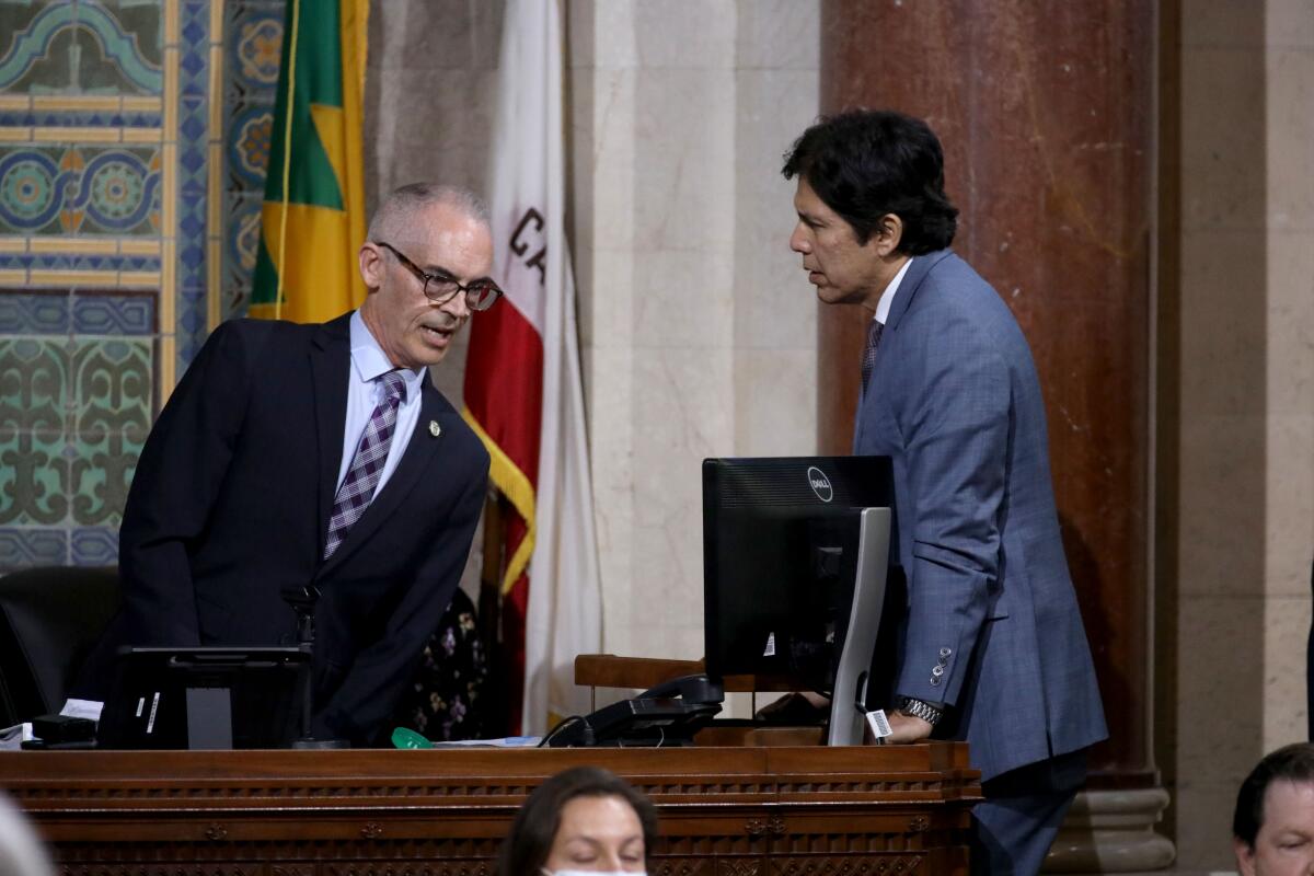 Two men speak at a desk